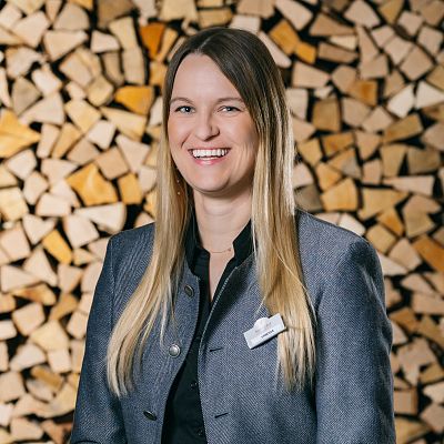 Portrait von Eventleiterin vor Brennholz im Hotel Kitzhof