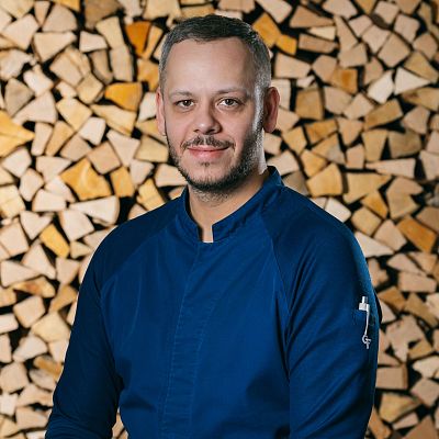 Portrait von Küchenchef vor Brennholz im Hotel Kitzhof
