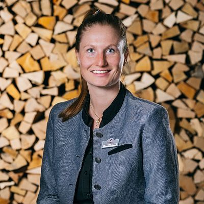 Portrait von Meetings und Eventmanagerin vor Brennholz im Hotel Kitzhof