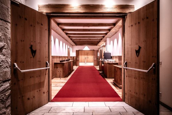Eleganter Hotelflur mit rotem Teppich und rustikalen Holztüren