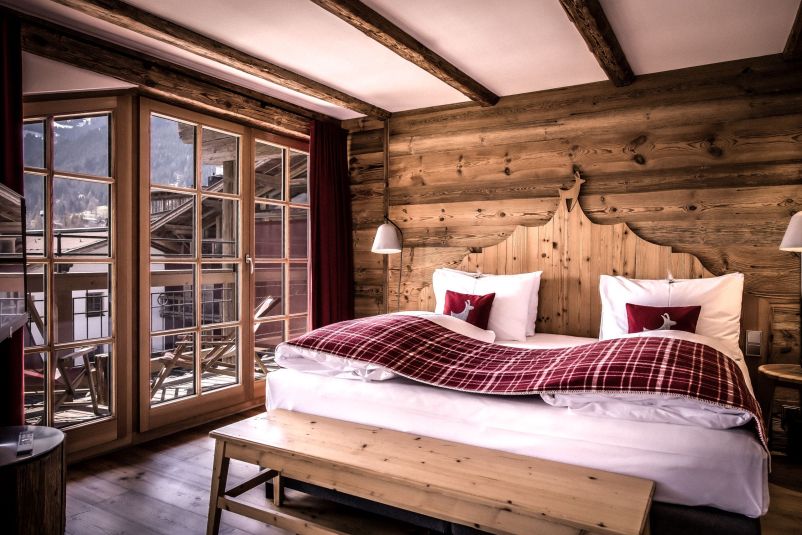Gemütliches Alpin-Schlafzimmer mit Holzwänden und Panoramablick