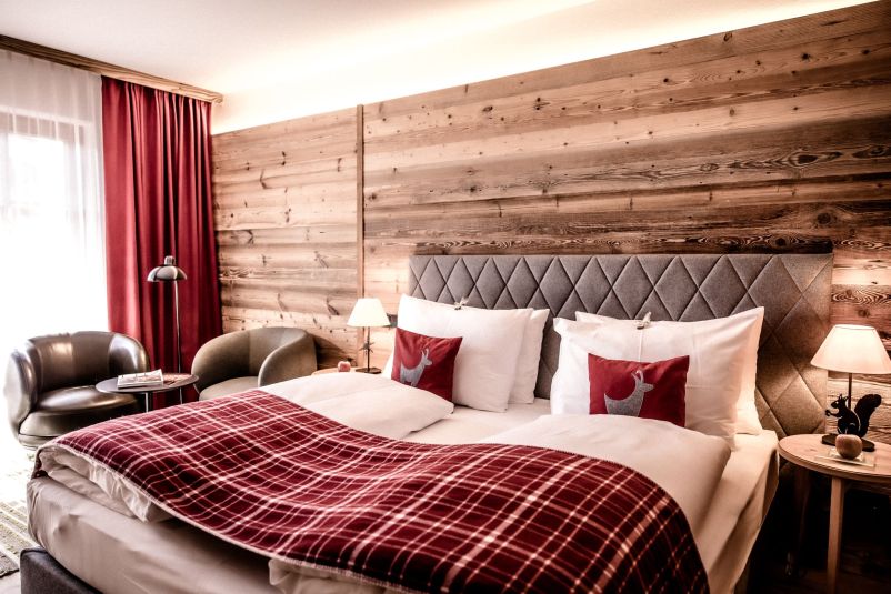 Gemütliches Hotelzimmer mit Alpenholz und roten Akzenten