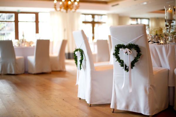 Elegante Hochzeitsstuhldekoration mit herzförmigen Kränzen