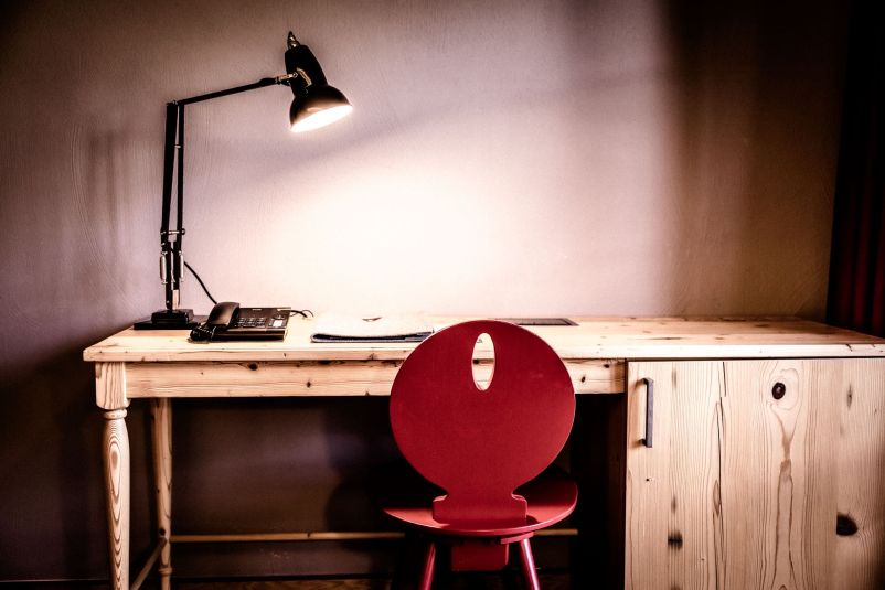 Minimalistischer Schreibtisch mit rotem Stuhl und Schreibtischlampe