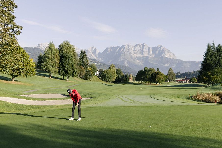 Mann am Golfplatz bei Morgenstimmung im Sommer mit Wildem Kaiser im Hintergrund