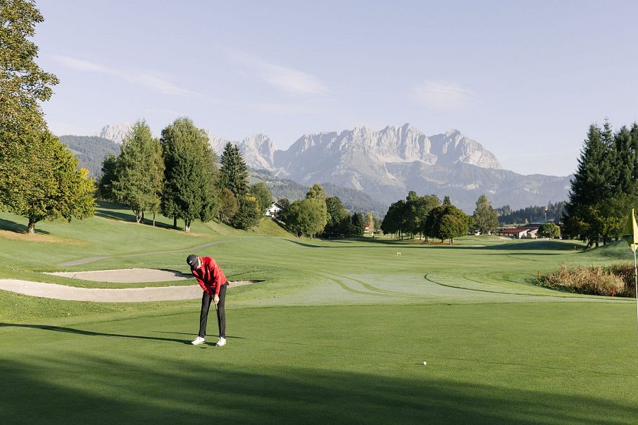 Mann am Golfplatz bei Morgenstimmung im Sommer mit Wildem Kaiser im Hintergrund