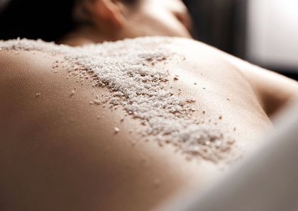 Nahaufnahme eines Rückens mit einer Salzbehandlung. Die Haut ist mit grobkörnigem Salz bedeckt, vermutlich während einer Wellness- oder Spa-Anwendung.